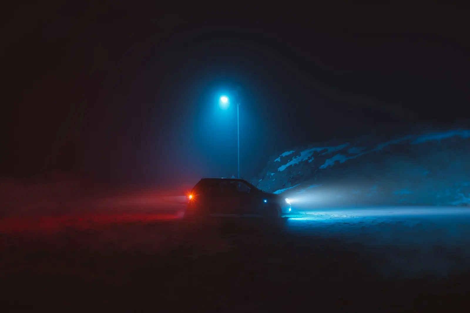 Coche en una carretera nocturna con niebla, iluminado por luces rojas y azules