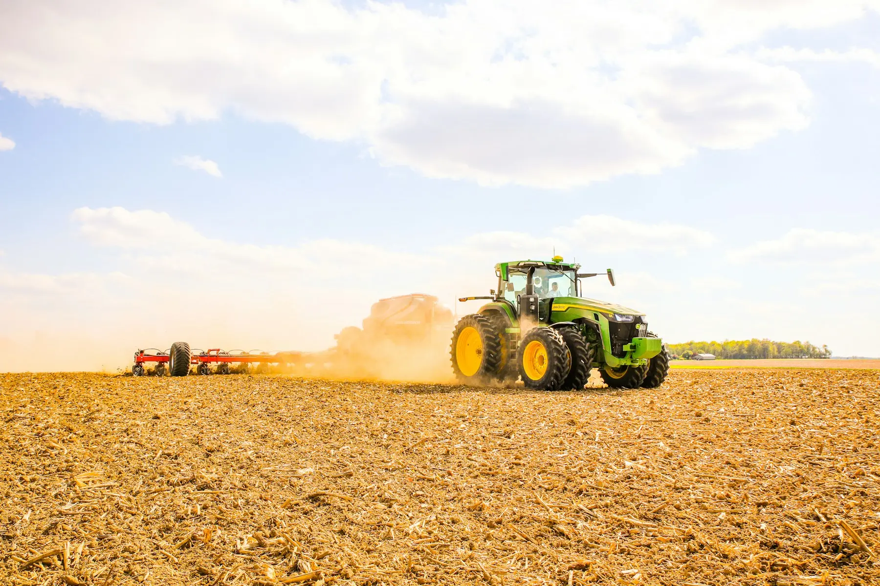 Tractor trabajando un campo de cultivo bajo el sol