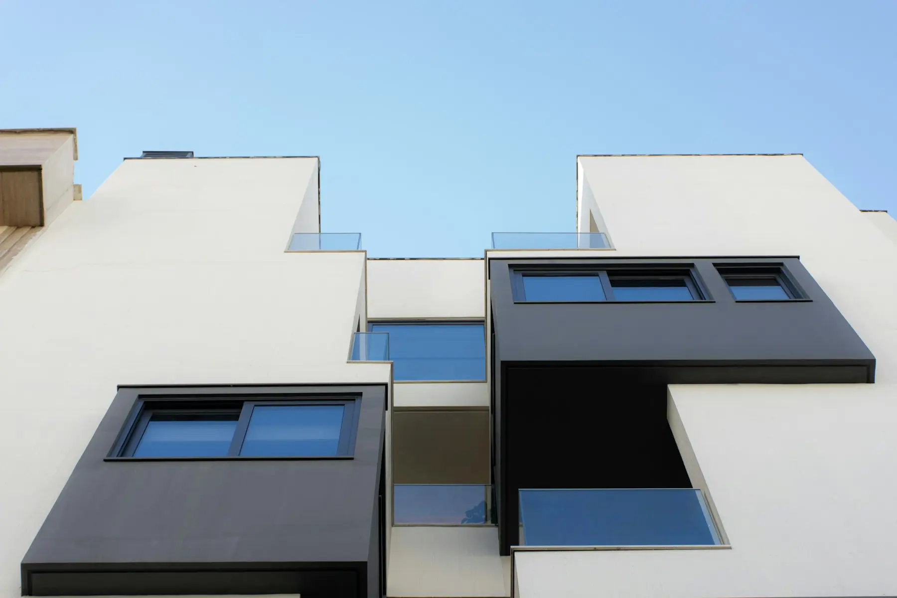 Fachada blanca de un edificio de viviendas bajo un cielo azul
