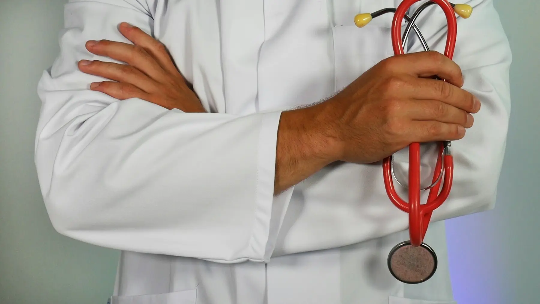 Médico con bata blanca y estetoscopio rojo