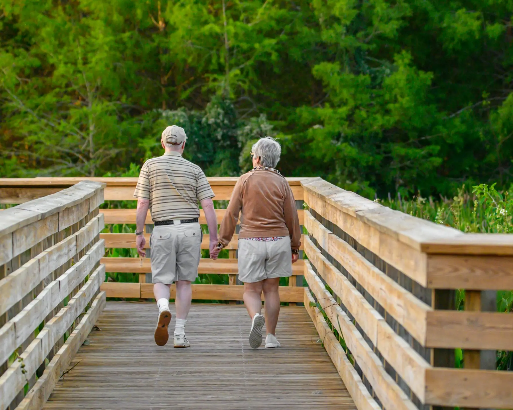 Pareja de personas mayores paseando por una pasarela de madera