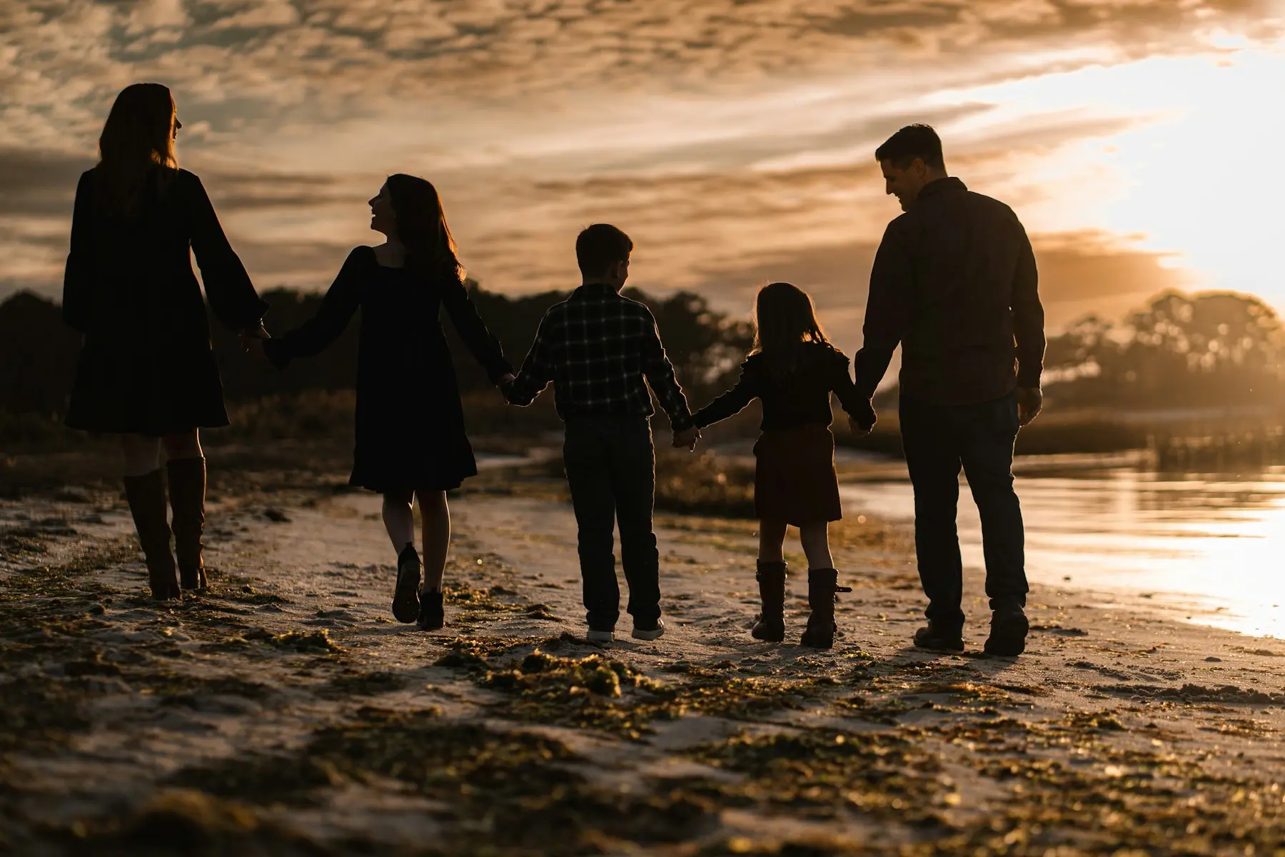 Familia paseando de la mano por la playa al atardecer